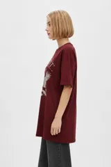 Remera bordó de manga corta y cuello redondo, con diseño holgado y estampado frontal de águila con la inscripción 'Wild West'.
