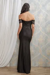 Vestido largo de fiesta color negro con corset estructurado y escote off-shoulder. Presenta detalles de encaje y bordados brillantes en el cuerpo, y una falda larga con tajo lateral profundo.