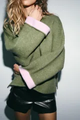 Jersey de punto de cuello redondo y manga larga con puños vueltos en contraste. Presenta un diseño holgado con aberturas laterales en el bajo.