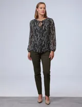 Blusa de gasa estampada en blanco y negro, marca Tahari. Tiene cuello redondo con escote en V y lazo, mangas largas con puño elastizado y forro a tono.