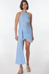 Vestido corto de lino celeste, con escote halter, falda drapeada asimétrica y cierre invisible en el lateral.