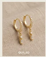 Aros tipo argolla de plata 925 con baño de oro, decorados con pequeñas circonias incrustadas en el aro y un dije colgante compuesto por una circonia redonda y una barra rectangular.
