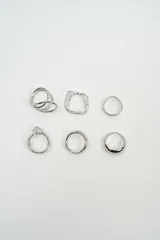 Set de seis anillos de metal plateado con diversos diseños, incluyendo formas geométricas, minimalistas y de estilo alambre.