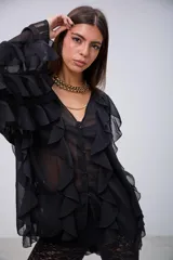 Blusa de tela semitransparente color negro, con diseño de volados verticales a lo largo del frente y en las mangas. Presenta cierre frontal con botones y cuello en V.