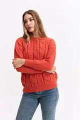 Buzo de punto color naranja con cuello redondo, diseño de trama combinada con detalles trenzados y terminaciones tejidas en puños y ruedo.
