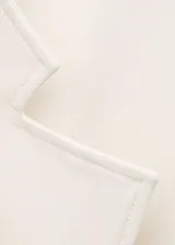 Chaqueta de mezcla de lana y poliéster color marfil, con solapas de muesca, cuello alto drapeado superpuesto y cierre cruzado con lazo ajustable del mismo tejido en la cintura.