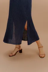 Vestido midi tejido de punto con diseño sin mangas y cuello halter. Presenta una silueta fluida con un panel de contraste en tono más claro a la altura de la cintura. Confeccionado con hilados italianos y sutiles toques de lurex.