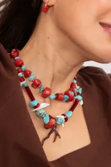 Collar corto elaborado con cuentas de turquesa reconstituida, piezas de nácar blanco, cuentas de cristal rojo y turquesa, y un dije central con forma de rama de coral.