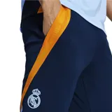 Calza deportiva azul marino de poliéster reciclado, con tecnología Aeroready, corte ajustado, cintura elástica con cordón, bolsillos laterales, puños con cremallera y escudo del Real Madrid termotransferido. Presenta paneles laterales con diseño de rayas horizontales en color naranja.
