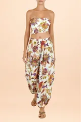 Pantalón tipo aladín con cintura elástica y puños ajustados en los tobillos. Presenta un estampado botánico multicolor sobre fondo blanco.