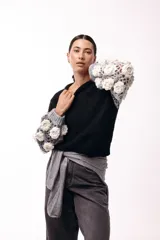 Sweater de punto con cuerpo liso en color negro y mangas largas tejidas en crochet gris con aplicaciones de flores en relieve color blanco.