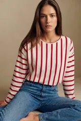 Remeron de corte oversize con cuello redondo y mangas largas. Presenta un diseño de rayas verticales en color rojo sobre base color crema.
