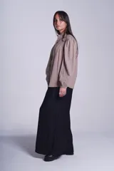 Camisa de color azul con cuello alto decorado con volados y lazo de ajuste. Presenta tablas decorativas en los hombros, cierre frontal con botones de nácar y mangas largas con puños elásticos que generan un efecto abullonado.