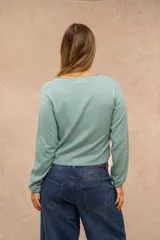 Saco de punto celeste de manga larga, con cuello redondo y cierre frontal de botones marrones. Presenta detalles de costura en contraste en el cuello, puños y ruedo.