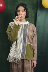 Buzo de manga larga con diseño patchwork que combina diferentes texturas y estampados, incluyendo tejido waffle verde oliva, tejido a rayas y cuadros en tonos grises y marrones, unidos con costuras visibles.