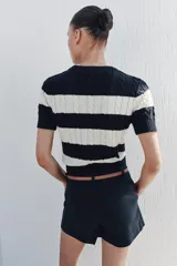 Sweater de punto con diseño de rayas horizontales anchas en color negro y blanco, cuello redondo y manga corta.