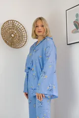 Pijama celeste con estampado de flores amarillas y blancas, compuesto por camisa de manga larga con botones y pantalón largo.
