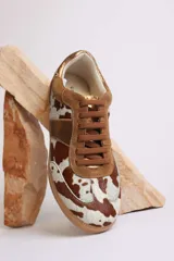 Zapatillas deportivas con estampado animal print de vaca en blanco y negro, con detalles en cuero sintético plateado en los laterales y talón.