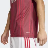 Camiseta de calentamiento Adidas del Arsenal FC, color bordó con estampado de rayas verticales sutiles. Presenta cuello redondo, logo de Adidas y escudo del club en contraste blanco, con tecnología Aeroready para mayor transpirabilidad.