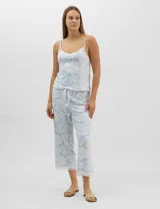 Conjunto de pijama de tres piezas en color celeste con estampado floral blanco y detalles de puntilla de encaje. Incluye una musculosa de breteles finos con escote en V, un capri con cintura elástica y cordón ajustable, y una camisa a juego.