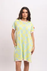 Vestido corto de punto de algodón, con estampado abstracto en tonos celestes y amarillos, escote redondo, mangas cortas y bolsillos laterales. Cuenta con terminaciones en color rosado.