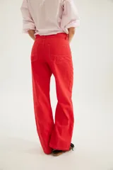 Pantalón de corte recto y tiro medio con costuras a la vista, bolsillos delanteros y traseros, y un detalle de pin de la marca en el ruedo.