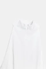 Vestido midi blanco, con cuello halter y falda con terminación en godets, lo que le da volumen y movimiento.