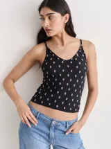 Musculosa negra con estampado floral rosa, breteles finos y escote en V.