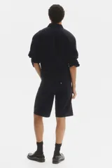 Bermuda de cinco bolsillos en denim de algodón grueso, con cintura estándar, cierre y botón, y piernas de corte relajado.