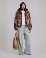 Campera con capucha de estilo híbrido, que combina una base de buzo con cierre frontal y paneles frontales y de mangas confeccionados en piel sintética de pelo largo en tonos marrones.