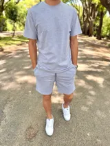 Conjunto deportivo gris melange compuesto por remera de manga corta y short con cordón ajustable en la cintura.
