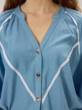 Camisa azul de lino con mangas 3/4, cuello redondo y detalles de ribetes en contraste.