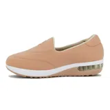 Zapato casual tipo slip-on de lycra color negro, con suela de plataforma blanca y cámara de aire en el talón. Presenta un aplique circular metálico con logo en el empeine.