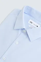 Camisa de corte regular fit en color celeste, con cuello italiano, manga larga con puños abotonados y cierre frontal de botones.