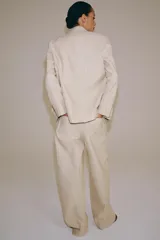Pantalón barrel de tiro medio confeccionado en hilatura con lino, color beige con diseño a rayas sutiles. Cuenta con cintura con trabillas, bolsillos laterales ocultos en costura, pierna ancha y cierre frontal con cremallera y botón.