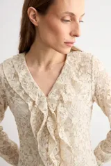 Blusa de encaje beige con escote en V y volados frontales, de manga larga.