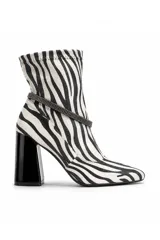 Bota corta de tacón alto ancho, color negro y blanco con estampado animal print de cebra, punta fina y detalle de tira con brillantes alrededor del tobillo.