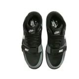 Championes Nike Air Trainer 1 de corte medio, con diseño en combinación de colores negro y gris. Presenta una correa ajustable sobre el empeine con el logo de la marca, el icónico swoosh lateral en color blanco y suela de goma con entresuela blanca.