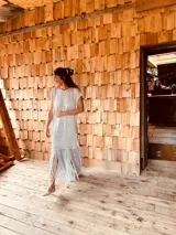 Vestido tejido color gris con hilado levemente brillante, corte oversized y flecos en el ruedo.