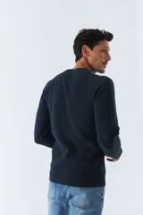 Sweater de punto color bordó, de corte clásico, cuello redondo y mangas largas. Presenta logo bordado en el pecho.