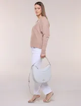 Cartera de hombro de silueta semicircular, marca Nanette Lepore. Modelo amplio de estructura flexible y diseño sofisticado, confeccionada en cuero sintético de textura graneada. Cuenta con cierre principal superior, asa corta integrada y correa larga cruzada regulable y desmontable. Presenta detalle de costura ornamental curva en el frente y logo metálico dorado aplicado en la parte inferior.
