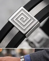 Pulsera de goma negra con detalles en acero inoxidable plateado que incluyen apliques con diseño de guarda griega y cierre de seguridad.