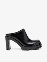 Zuecos negros de cuero con punta redonda y detalle de logo D en la puntera. Taco cuadrado alto y suela track.