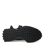 Championes urbanos New Balance modelo 327, color negro, confeccionados en una combinación de malla y material sintético. Presentan el logo 'N' característico en el lateral, cordones al tono y una suela de goma con relieve que se extiende hacia el talón.