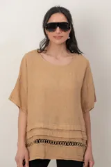 Blusa de lino color blanco, de corte amplio, con escote redondo, mangas cortas y detalle de guarda calada horizontal en la parte inferior.