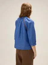 Camisa azul de lino con mangas 3/4, cuello redondo y detalles de ribetes en contraste.