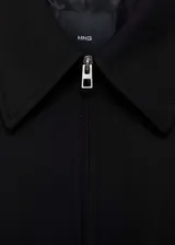 Chaqueta negra de diseño oversize con cuello camisero y cierre frontal de cremallera. Cuenta con forro interior y bolsillos laterales.