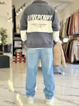 Buzo de cuello polo y medio cierre, con diseño de bloques de color en gris y blanco, de corte oversize y mangas largas.