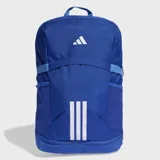 Mochila Adidas modelo Tiro, color azul con detalles en blanco. Cuenta con compartimento principal con cierre, bolsillos laterales de malla y correas acolchadas ajustables. Presenta el logo de la marca en la parte superior y las tres tiras características en la parte inferior frontal.
