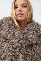 Campera corta de pelo sintético con textura rizada y voluminosa, de diseño envolvente y acabado suave.